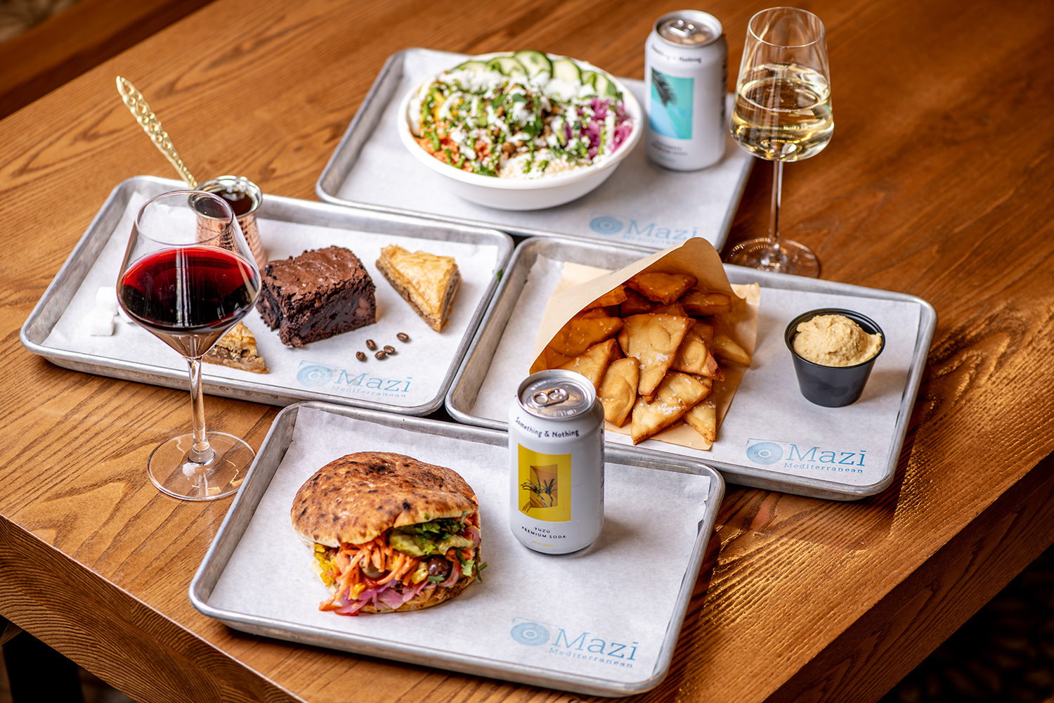 A table of Mazi bowls, pitas, chips and desserts